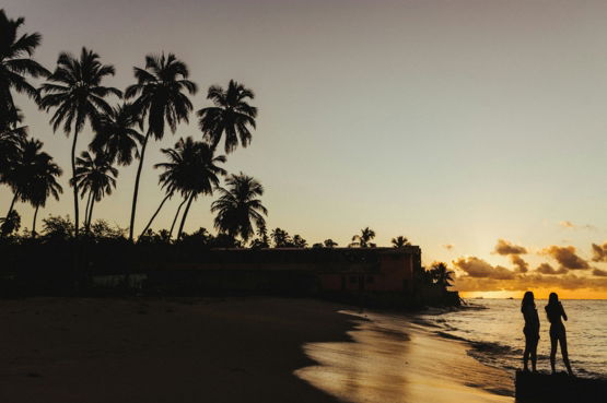 silhouette of two person on seashore during golden hour